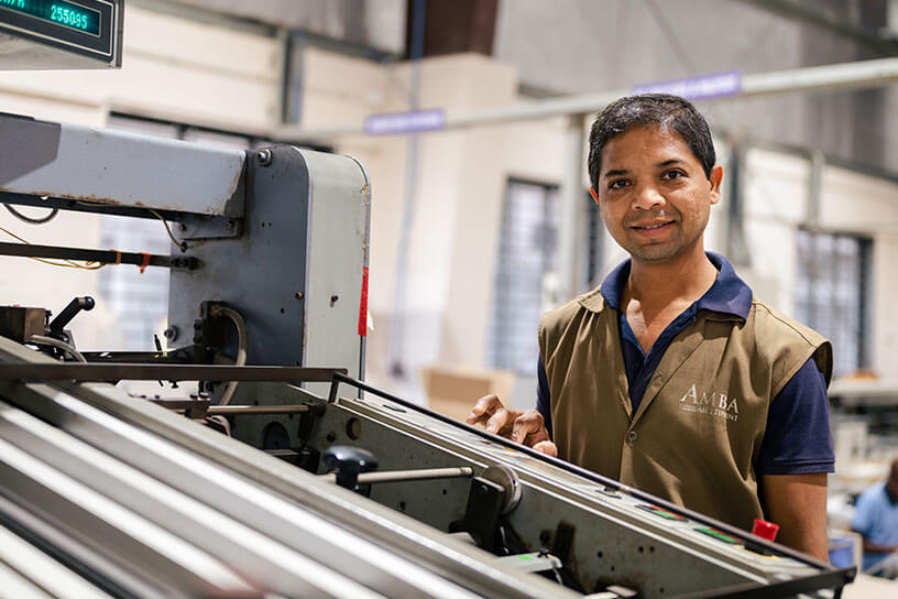 A man is standing near the Offset printing & packaging machine 