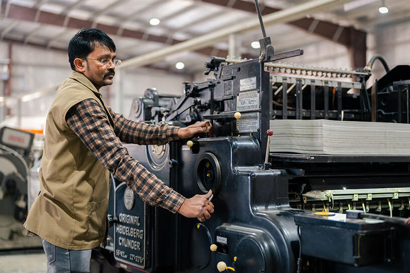 A Man is working on Printing and packaging machine in AMBA offset printer